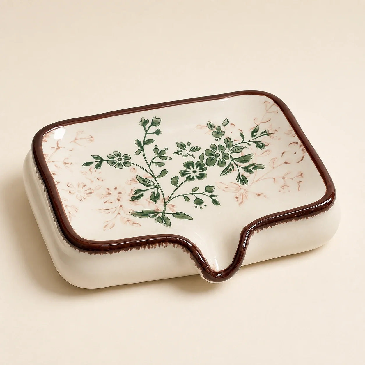 Close view of the brown rim and green floral motif on the ceramic soap dish