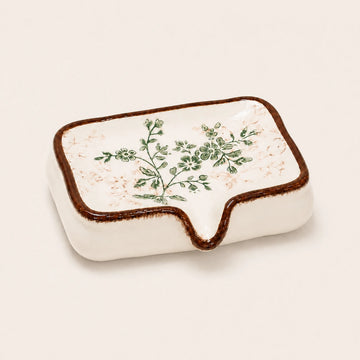 Vintage botanical ceramic soap dish on a warm ivory studio background