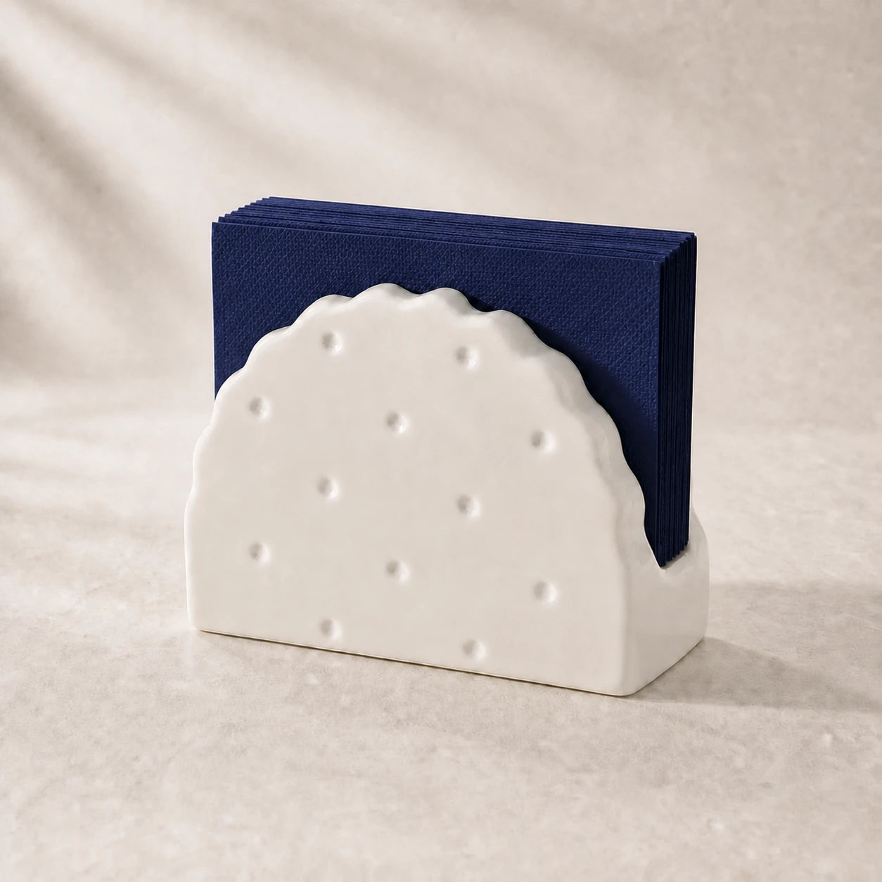 Alabaster White Soda Cracker ceramic napkin holder with navy napkins on pale stone