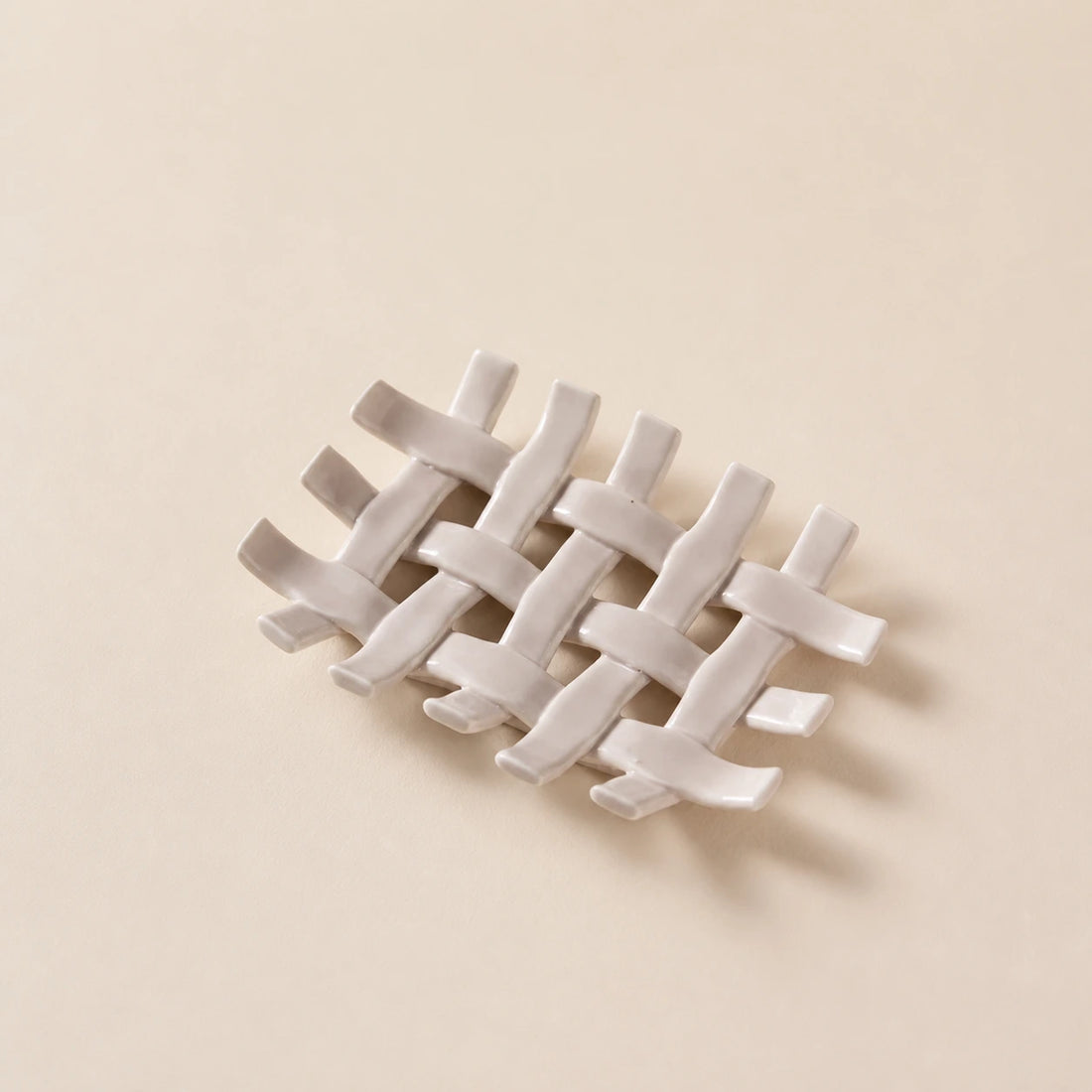 Warm apricot woven ceramic soap dish on a softly lit ivory studio surface