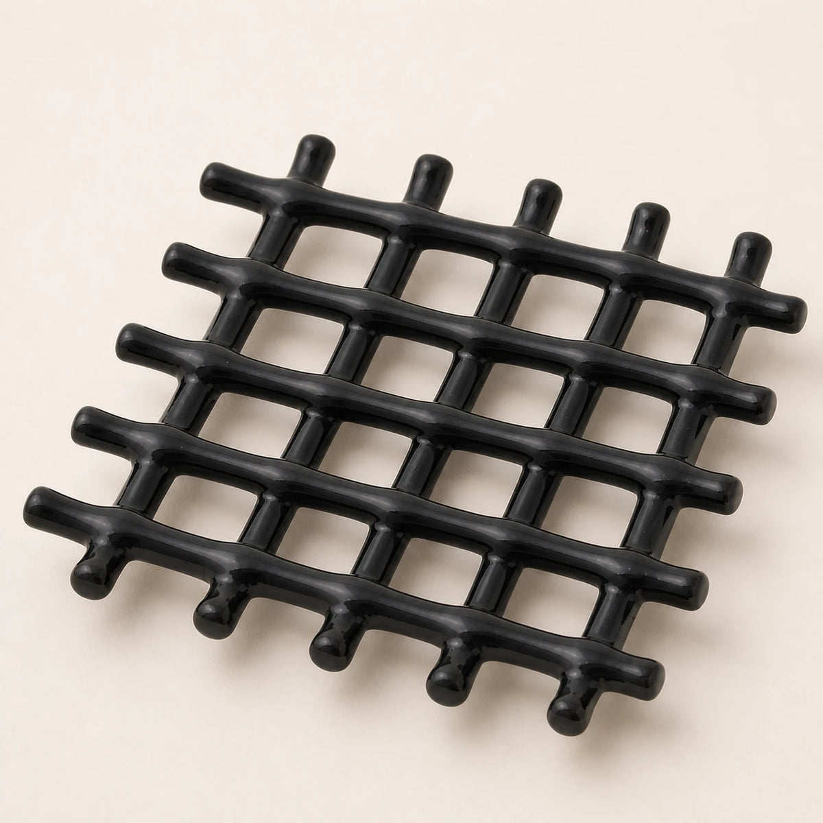 Vue rapprochée du treillis en céramique noire brillante formé de tiges croisées aux extrémités arrondies
