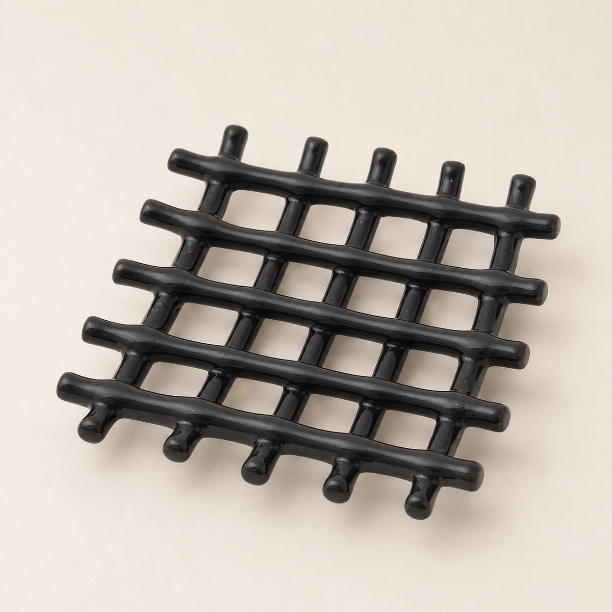 Porte-savon carré en céramique noire brillante aux tiges croisées en treillis sur fond ivoire chaleureux