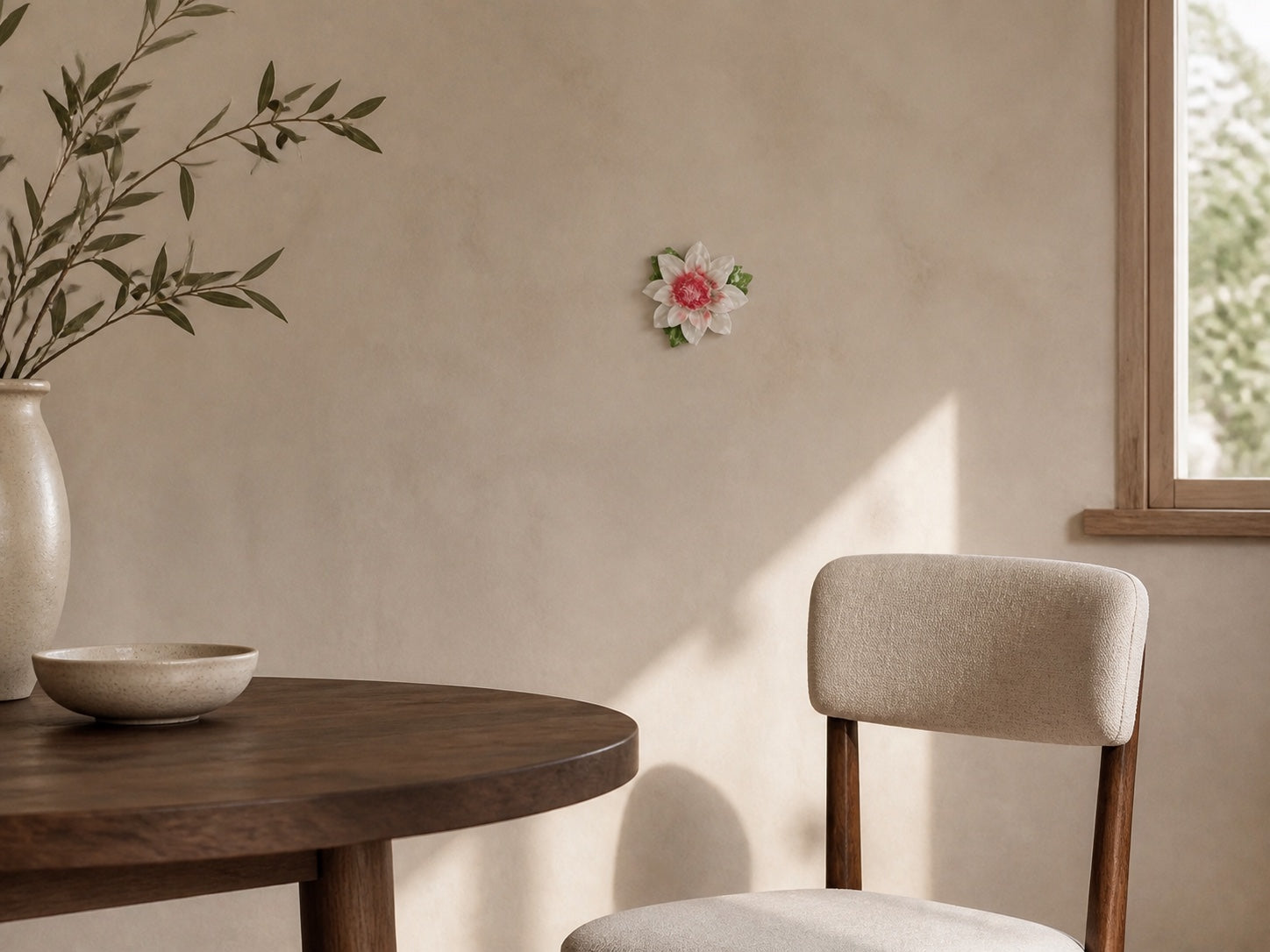 Small rose-red ruffled ceramic wall flower styled beside a warm dining nook.